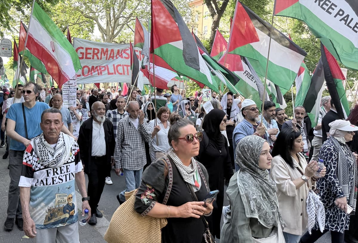 Filistin ve İran bayrakları taşıyan kalabalık bir protestocu grubu sokakta yürüyor.