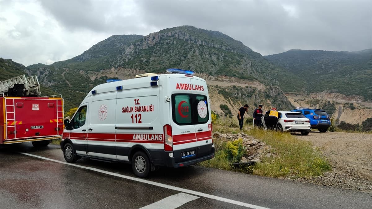 Dağlık yolda ambulans, itfaiye ve polis araçları ile bir olay yeri. Görevliler araçların yanında duruyor.